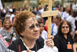 A woman holds a cross during a tribute to those who died in the dam disaster last year in Brumadinho, Brazil, Jan. 25, 2020.