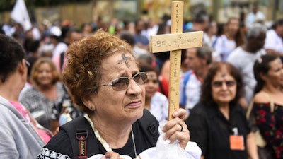 A woman holds a cross during a tribute to those who died in the dam disaster last year in Brumadinho, Brazil, Jan. 25, 2020.