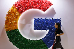 In this Nov. 5, 2018, file photo, a woman walks past the logo for Google at the China International Import Expo in Shanghai.