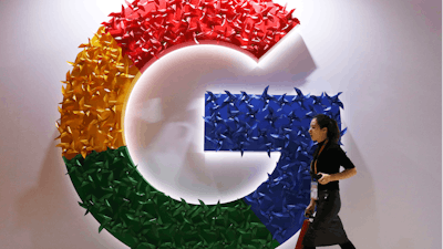 In this Nov. 5, 2018, file photo, a woman walks past the logo for Google at the China International Import Expo in Shanghai.