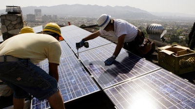 Workers from California Green Design install solar electrical panels on the roof of a home in Glendale, Calif. in 2010.