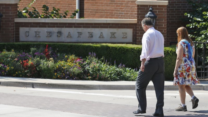 In this Sept. 29, 2015, file photo, two people walk past an entrance to the Chesapeake Energy Corp. campus in Oklahoma City.