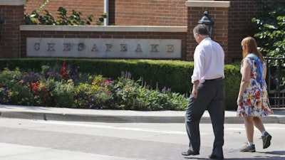 In this Sept. 29, 2015, file photo, two people walk past an entrance to the Chesapeake Energy Corp. campus in Oklahoma City.