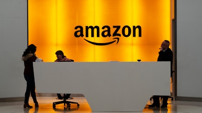 In this Feb. 14, 2019, file photo, people stand in the lobby of Amazon offices in New York.