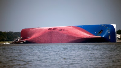 In this Sept. 9, 2019, file photo, a Moran tugboat nears the stern of the capsizing vessel Golden Ray near St. Simons Sound off the coast of Georgia.