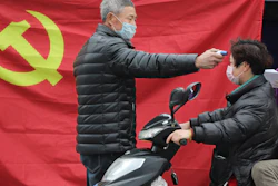 A volunteer takes the temperature of a scooter driver at a roadside checkpoint in Hangzhou, China, Feb. 3, 2020.