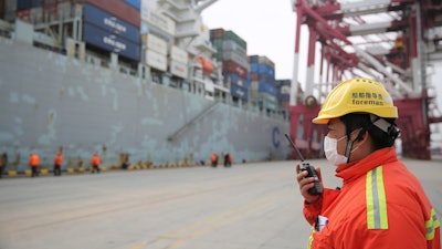 In this Feb. 4, 2020, photo, a foreman wears a face mask at a container port in Qingdao, China.