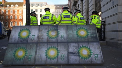 Police officers stand near activists outside BP's headquarters, St James' Square, London, Feb. 5, 2020.