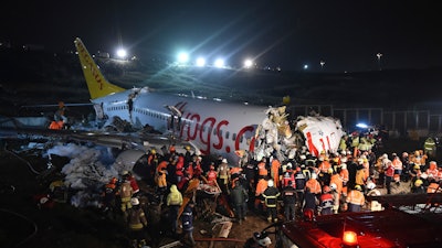 Rescue members and firefighters work around the wreckage of a plane after it skidded off the runway at Istanbul's Sabiha Gokcen Airport, Feb. 5, 2020.