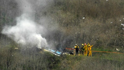 In this Jan. 26, 2020, file photo, firefighters work the scene of a helicopter crash where former NBA star Kobe Bryant died in Calabasas, Calif.