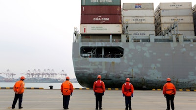 In this Feb. 4, 2020, photo, workers watch a container ship arrive at a port in Qingdao, China.