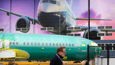 A Boeing worker walks past a 737 model fuselage and mural in Renton, Wash., Dec. 16, 2019.