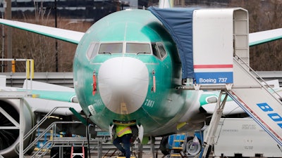 In this Dec. 16, 2019, file photo, a worker looks up underneath a Boeing 737 Max jet in Renton, Wash.