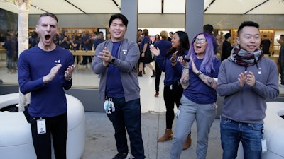 Apple employees greet customers as they wait to enter the Union Square store in San Francisco, Nov. 3, 2017.