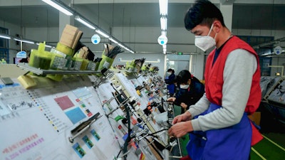 Masked workers assemble auto wiring at a factory in Qingdao, China, Feb. 13, 2020.