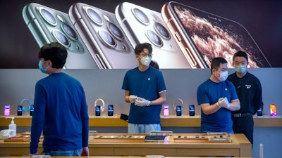 Employees wear face masks as they stand in a reopened Apple Store in Beijing, Feb. 14, 2020.