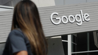 A woman walks below a Google sign on the company's campus in Mountain View, Calif., Sept. 24, 2019.
