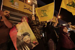 Supporters of Hezbollah leader Sayyed Hassan Nasrallah hold his pictures and wave Hezbollah flags in a southern suburb of Beirut, Lebanon, Oct. 25, 2019.