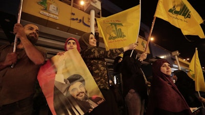 Supporters of Hezbollah leader Sayyed Hassan Nasrallah hold his pictures and wave Hezbollah flags in a southern suburb of Beirut, Lebanon, Oct. 25, 2019.