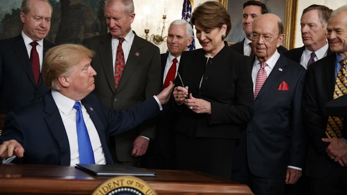 President Donald Trump hands a pen to Lockheed Martin CEO Marillyn Hewson after signing a memorandum imposing tariffs and investment restrictions on China, March 22, 2018, in the White House.
