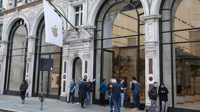 Staff members stand outside of a London Apple Store informing people of its closure, March 14, 2020.