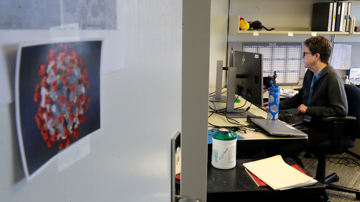 Dr. Lisa Jackson, a senior investigator at the Kaiser Permanente Washington Health Research Institute, works in her office with an image of COVID-19 taped to her door, March 15, 2020, in Seattle.