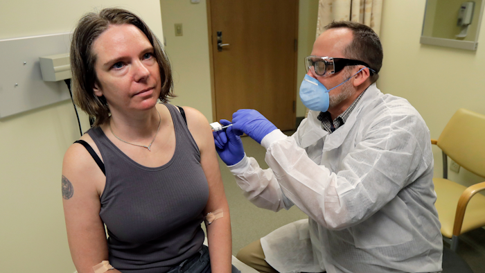 A pharmacist gives Jennifer Haller the first shot in the clinical trial of a potential vaccine for COVID-19, March 16, 2020, at the Kaiser Permanente Washington Health Research Institute in Seattle.