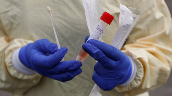 A nurse holds swabs and test tube to test people for COVID-19 at a drive through station set up in the parking lot of the Beaumont Hospital in Royal Oak, Mich., March 16, 2020.