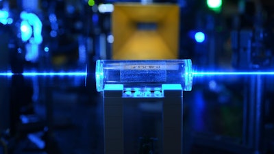 Atoms in a glass vapor cell excited with laser beams to Rydberg states to detect electric fields.