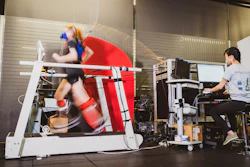 Graduate student Delaney Miller runs on a treadmill aided by the ankle exoskeleton emulator. Fellow graduate student Guan Rong Tan controls the emulator and monitors Miller's gait and respiration.