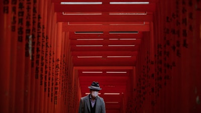 A man with a mask walk through torii gates at the Hie Shrine In Tokyo, March 1, 2020.