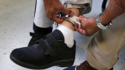 A therapist checks the ankle strap of an electrical shocking device on a student during an exercise program at the Judge Rotenberg Educational Center in Canton, Mass., Aug. 13, 2014.