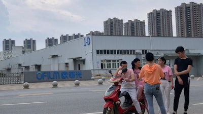 Residents chat near the entrance to an OFILM factory in Nanchang, China, June 5, 2019.
