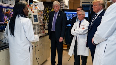 Dr. Kizzmekia Corbett, left, senior research fellow and scientific lead for coronavirus vaccines and immunopathogenesis team in the Viral Pathogenesis Laboratory, talks with President Donald Trump at the National Institutes of Health, Bethesda, Md., March 3, 2020.