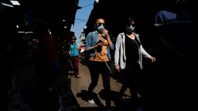 People wear face masks at a food market in Tel Aviv, March 15, 2020.