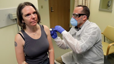 A pharmacist gives Jennifer Haller the first shot in the clinical trial of a potential vaccine for COVID-19, March 16, 2020, at the Kaiser Permanente Washington Health Research Institute in Seattle.
