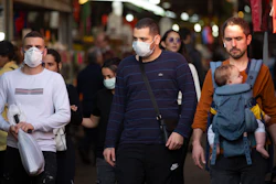 People wear face masks as they shop at a food market in Tel Aviv, March 16, 2020.