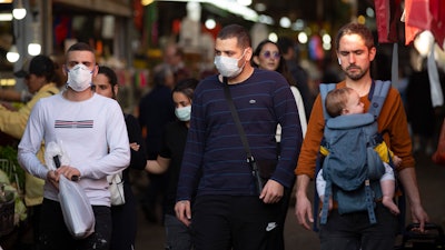 People wear face masks as they shop at a food market in Tel Aviv, March 16, 2020.