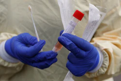 A nurse holds swabs and test tube to test people for COVID-19 at a drive through station set up in the parking lot of the Beaumont Hospital in Royal Oak, Mich., March 16, 2020.