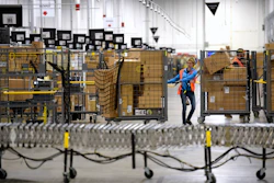 Associates move bins filled with products at the loading dock of Amazon's fulfillment center in Livonia, Mich., March 23, 2018.