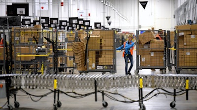 Associates move bins filled with products at the loading dock of Amazon's fulfillment center in Livonia, Mich., March 23, 2018.