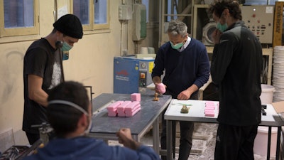 Serge Bruna, center, and soap artisans cut bars of soap at the Licorne factory in Marseille, France, March 16, 2020.