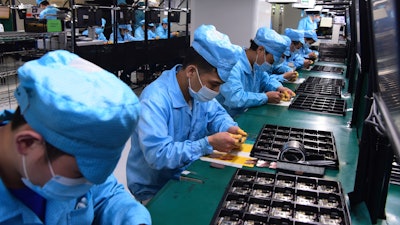 Workers wear masks at a factory for telecom company OPPO in Dongguan, China, Feb. 13, 2020.
