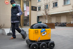 A maintenance worker looks at a robot outside the offices of ZhenRobotics in Beijing, March 18, 2020.