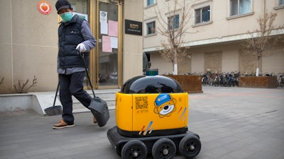 A maintenance worker looks at a robot outside the offices of ZhenRobotics in Beijing, March 18, 2020.