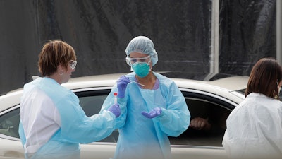 Health care personnel test a person in the passenger seat of a car at a Kaiser Permanente medical center in San Francisco, March 12, 2020.