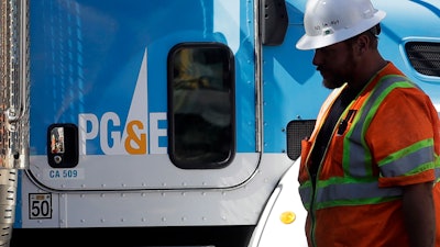A Pacific Gas & Electric worker walks in front of a truck in San Francisco, Aug. 15, 2019.