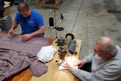 Bill Purdue, left, cuts pieces of fabric while Mike Rice sews them into face masks in Rice's auto body and upholstery shop in Washington, Ind., March 22, 2020.