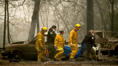 Firefighters and deputies carry the body of a Camp Fire victim at the Holly Hills Mobile Estates in Paradise, Calif., Nov. 14, 2018.