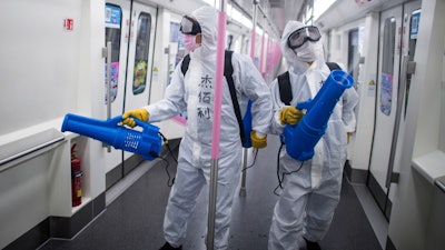 Workers disinfect a subway train in Wuhan, March 23, 2020.